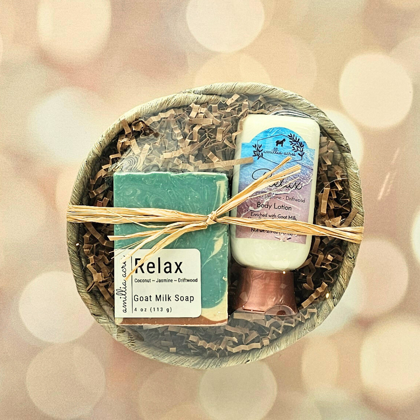 The Amillia Acres Small Gift Basket features a goat milk bar soap, body lotion, and exfoliating pouch in brown crinkle paper, all tied with raffia and beautifully presented against a soft background.