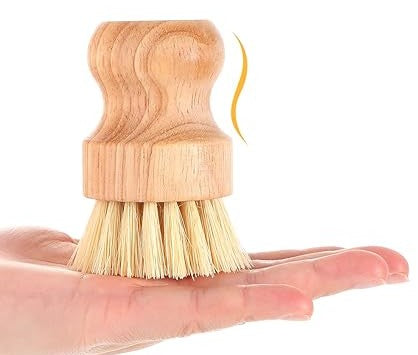 A hand holds the Amillia Acres Dish Scrubber, featuring durable bristles and a rounded, ergonomic handle for easy grip. This eco-friendly scrubber is perfect for everyday dishwashing.