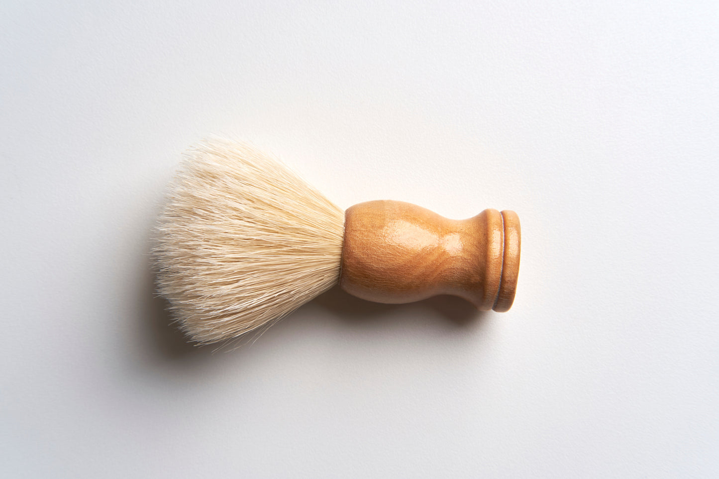 The Amillia Acres Classic Shave Brush features a light wooden handle and soft, cream-colored bristles, ideal for enhancing your grooming or shaving routine.