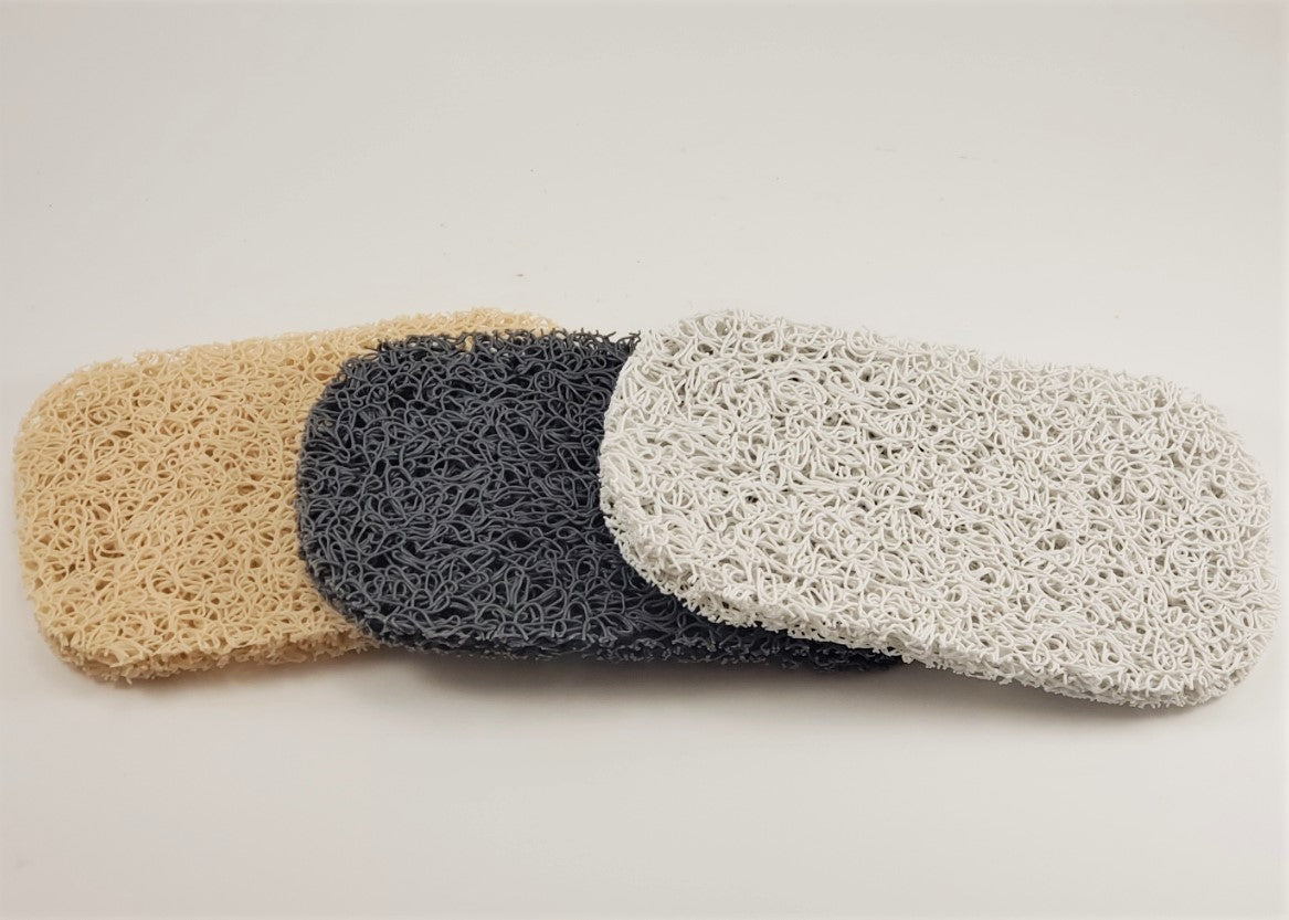 On a simple white background, three overlapping rectangular pads in beige, gray, and white showcase their textured, net-like surface. These Soap Savers from Amillia Acres are designed to extend the life of your soap.
