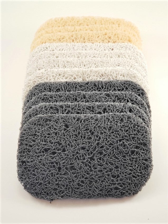A stack of three Amillia Acres Soap Savers features a loofah-like texture; the top two have a pale color while the bottom one is dark gray. These are perfect for extending the life of your soap and maintaining cleanliness on any light background surface.