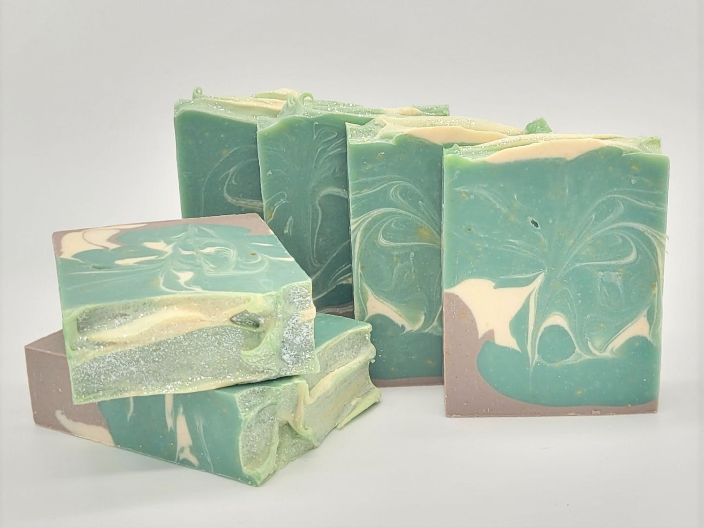 Five bars of Amillia Acres' "Relax" Goat Milk Soap, featuring natural oils and swirling designs in green, cream, and brown hues, are neatly stacked against a plain white background.