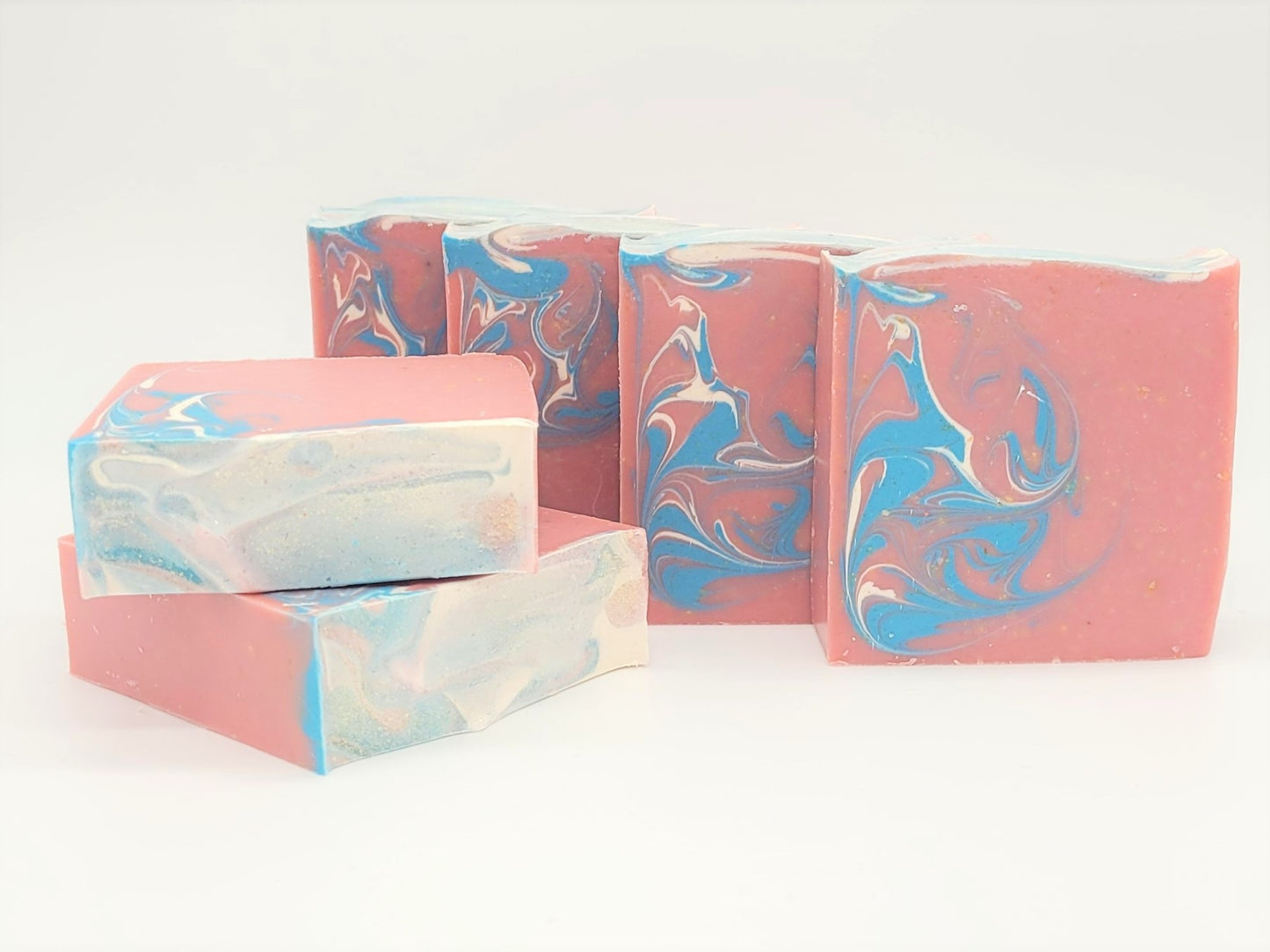 Escape Goat Milk Soaps by Amillia Acres feature handcrafted swirls of pink, blue, and white and stand upright to invite you into their gentle fragrance against a simple backdrop.