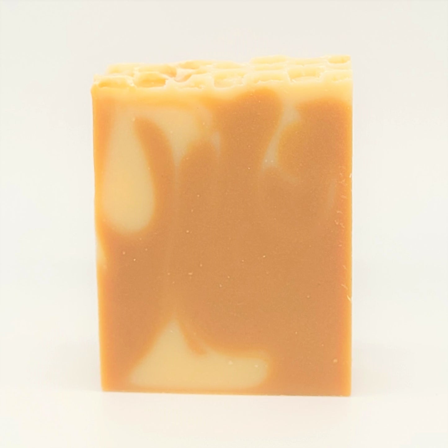The Nourish Goat Milk Soap by Amillia Acres, handmade with natural oils, features a smooth texture and an orange and cream swirl pattern. It stands upright against a plain white background.