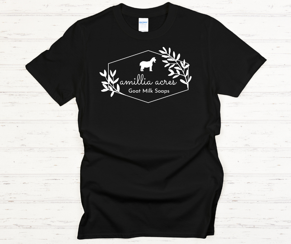 This Amillia Acres ~ Goat Milk Soaps and Lotions short-sleeve t-shirt is made from 100% preshrunk cotton and features a small goat graphic above the text "Amillia Acres" and "Goat Milk Soaps," all elegantly framed by decorative branches.
