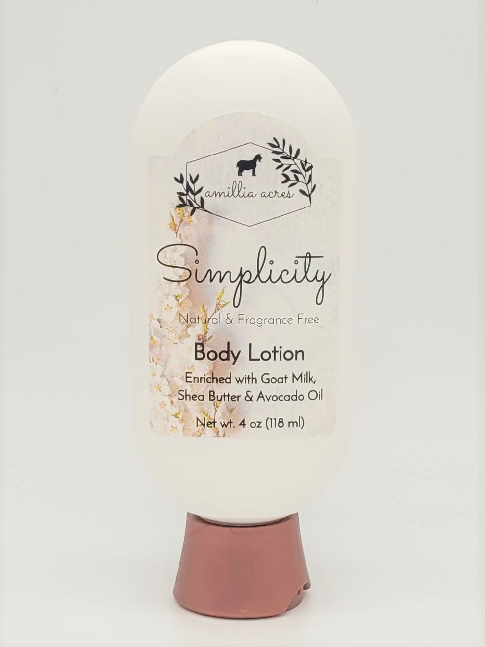 A 4 oz white bottle of Amillia Acres' "Simplicity" Goat Milk Lotion, enriched with goat milk, shea butter, and avocado oil. This natural, fragrance-free moisturizer features a pink-tinted cap.