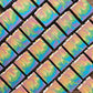 Amillia Acres' Flower Child Goat Milk Soap bars are displayed diagonally, featuring a swirling rainbow pattern in blue, green, yellow, and pink. The handcrafted bars have a smooth, vibrant texture infused with natural oils.