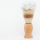The Amillia Acres Classic Shave Brush features a wooden handle and upright bristles crowned with rich white shaving cream, displayed against a plain white background—a grooming essential.