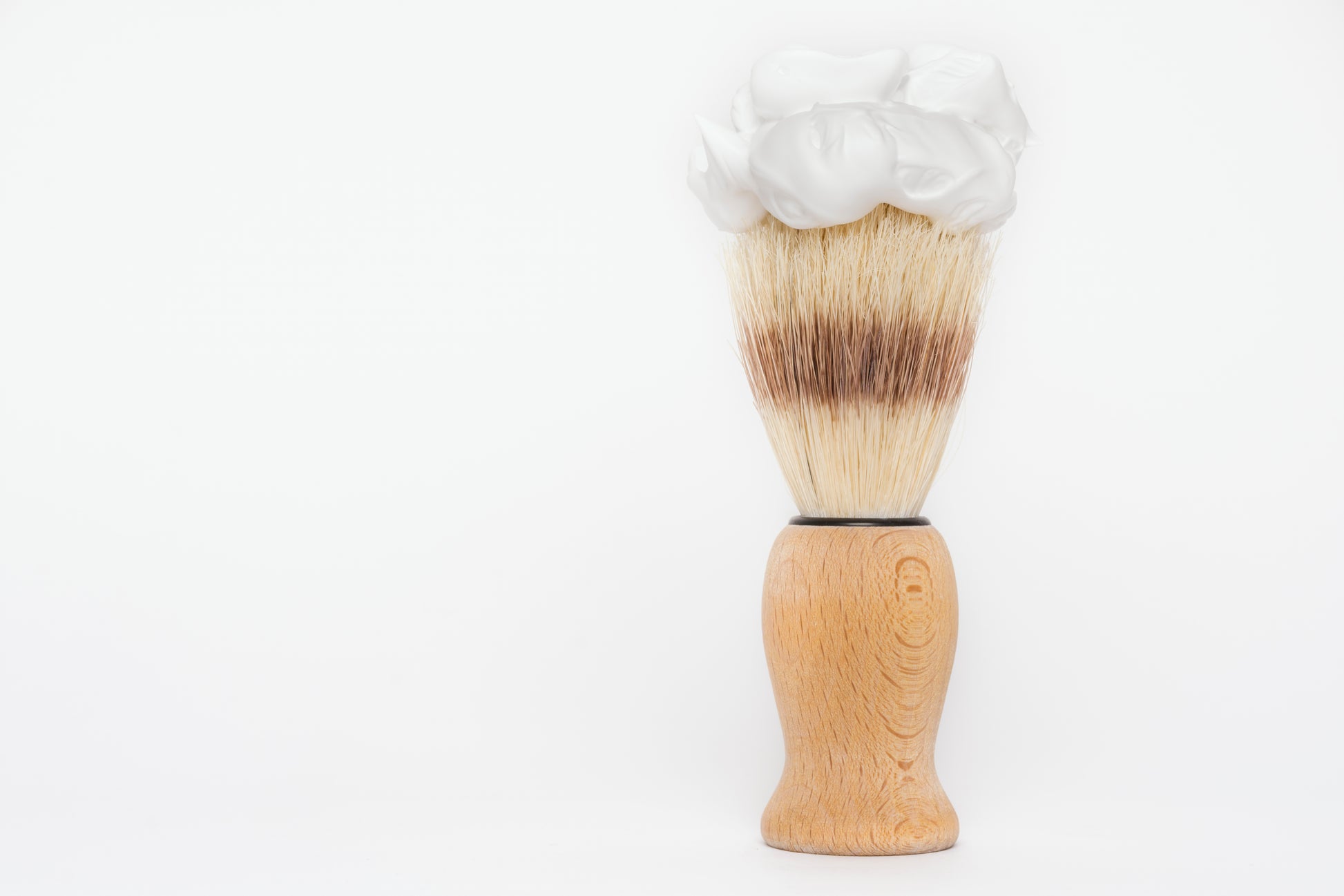The Amillia Acres Classic Shave Brush features a wooden handle and upright bristles crowned with rich white shaving cream, displayed against a plain white background—a grooming essential.