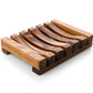 The Amillia Acres Wooden Soap Lift features a natural wood, rectangular design with curved grooves and four short legs, offering a stylish and functional way to keep your soap dry. Displayed on a white background.