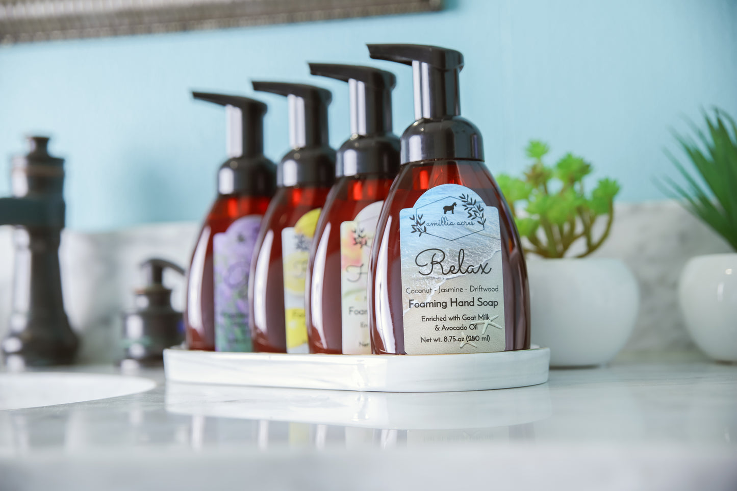 Four Amillia Acres ~ Goat Milk Soaps and Lotions foaming hand soap bottles with pumps sit on a white tray by a succulent, ready to pair with your REFILL - Foaming Hand Soap for your favorite custom scent.