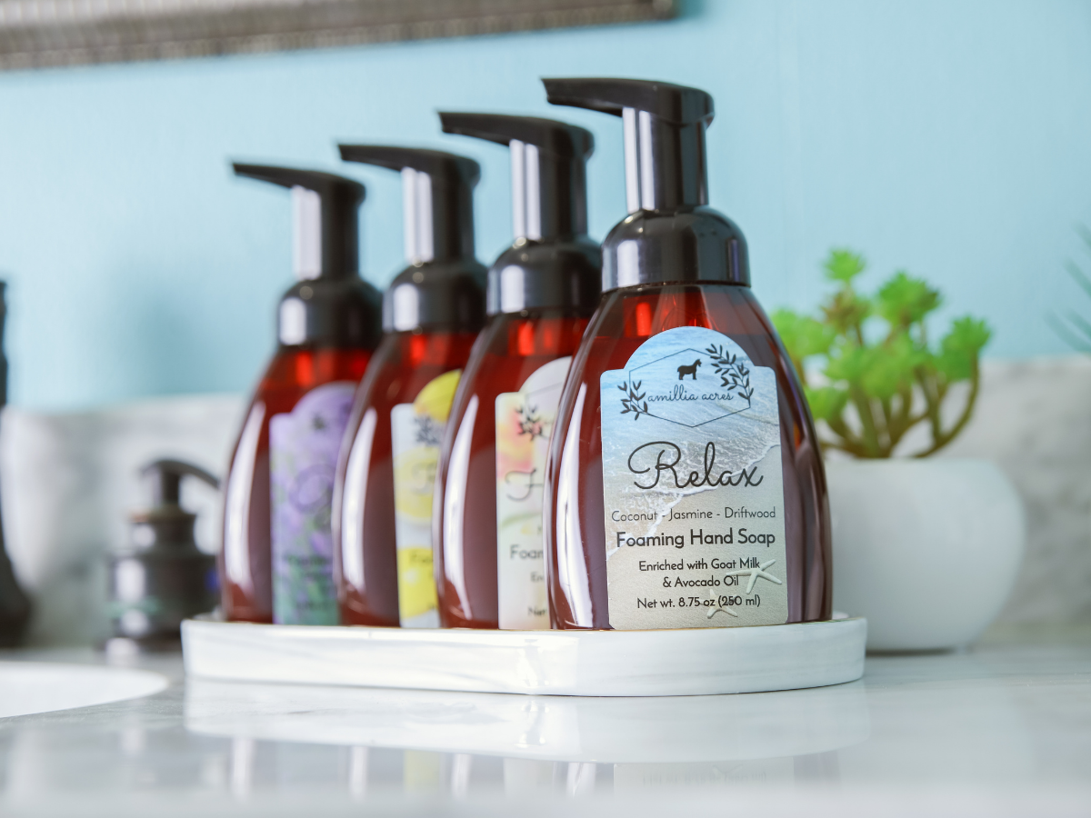Four amber-colored foaming hand soap bottles of ALL Fall & Holiday Varieties | Foaming Hand Soap with black pumps arranged in a row on a white tray.