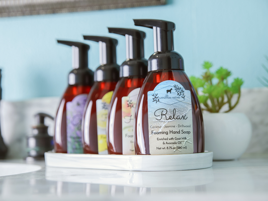 Four amber-colored foaming hand soap bottles of ALL Fall & Holiday Varieties | Foaming Hand Soap with black pumps arranged in a row on a white tray.