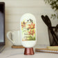 A bottle of Amillia Acres “Happiness” Goat Milk Lotion sits on a desk near a laptop and mug. Its label features nourishing shea butter and avocado oil, offering rich hydration for your skin.