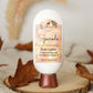 A bottle of Amillia Acres’ Sparkle Goat Milk Lotion rests on a wooden coaster with autumn leaves, featuring cranberry and sweet orange scent enriched with shea butter and avocado oil.