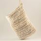 The Exfoliating Soap Saver Bag by Amillia Acres, a beige, handwoven mesh-style accessory, is displayed against a plain, light-colored background. Crafted from natural sisal, its texture boasts intricate loops and knots for an airy and natural appearance. Perfect for gently exfoliating your skin during daily routines.