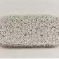 The Soap Saver by Amillia Acres is a rectangular scrubbing sponge featuring a textured, curly surface to prolong the lifespan of your soap, displayed on a plain white background.