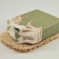 A handcrafted bar of soap with a green and white marbled design, featuring hints of blue, rests gracefully on the beige-textured Amillia Acres' Soap Saver to help maximize the lifespan of your soap.