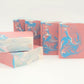 Escape Goat Milk Soaps by Amillia Acres feature handcrafted swirls of pink, blue, and white and stand upright to invite you into their gentle fragrance against a simple backdrop.