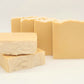 Stacks of Amillia Acres' I LOVE This Bar goat milk soaps, with some displaying a marbled pattern and uneven top edges, rest against a plain white background, highlighting their artisanal charm.