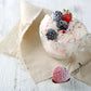 A glass cup with Black Raspberry & Vanilla ice cream, topped with blackberries and strawberries, rests on a beige cloth on a white wooden table. Nearby, a sugar-dusted strawberry adorns a spoon. Complement this scene with "Dazzle" Goat Milk Lotion from Amillia Acres ~ Goat Milk Soaps and Lotions.