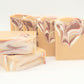 Five Comfort Goat Milk Soaps by Amillia Acres, crafted with natural oils and swirling cream, pink, and brown patterns, are displayed against a white background. Three bars stand upright while two lie flat in the foreground, showcasing their handmade beauty.